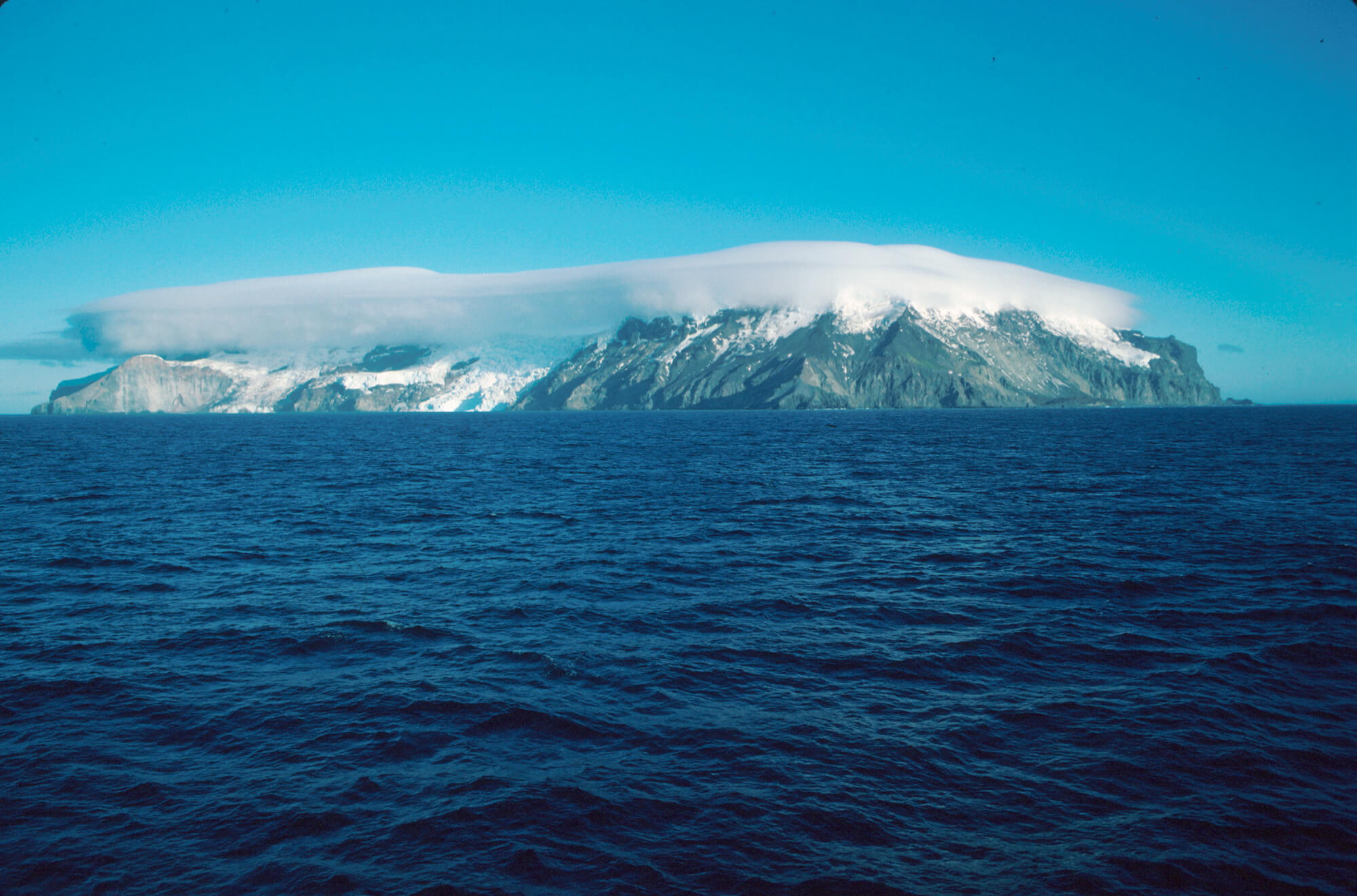 Vue panoramique de l’île Bouvet depuis la mer sous un ciel bleu